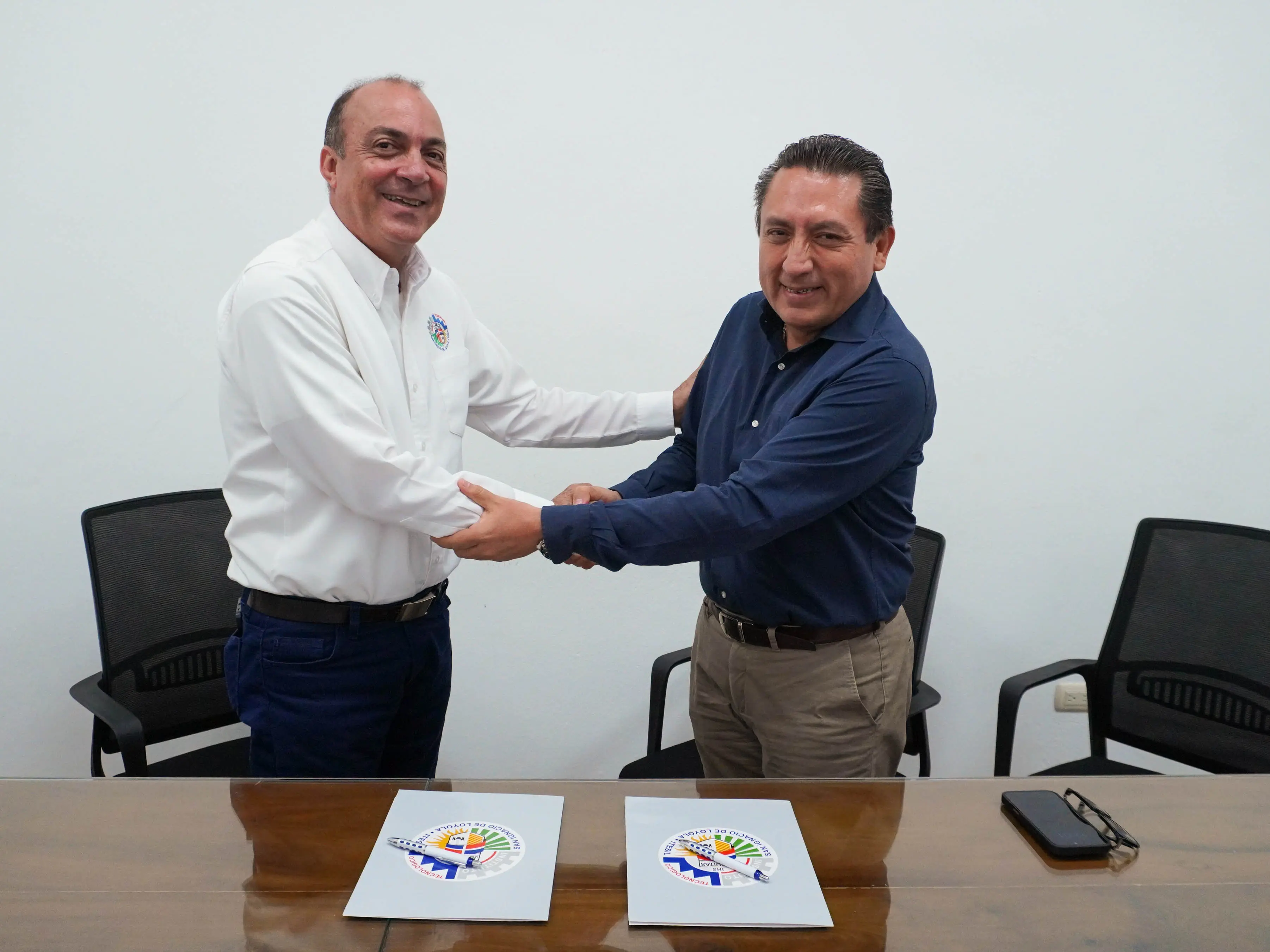 El P. José Núñez Mármol, S.J., director del Instituto Tecnológico San Ignacio de Loyola, y el señor Mario Medina, gerente de Sostenibilidad en Industrias San Miguel (ISM), estrechándose las manos con expresión cordial durante la firma de un convenio.